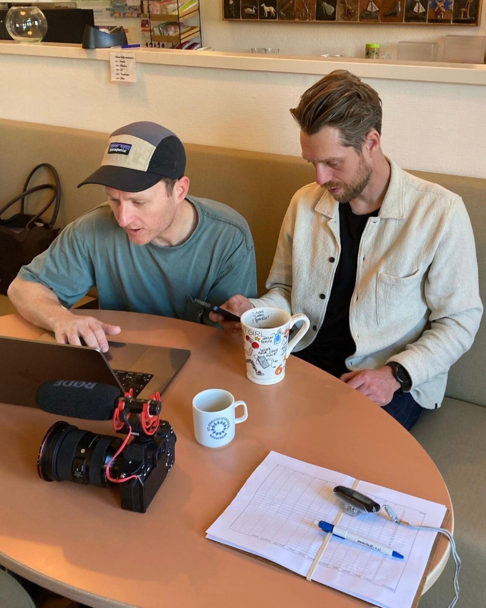 Sircle aan het werk: Aris en Sebas op locatie tijdens de PR-activatie, met camera, RØDE-mic en stappentellers op tafel